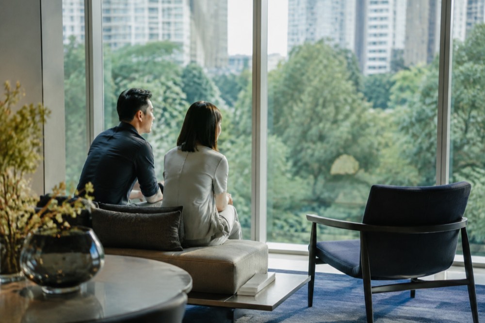 A couple sitting in a showflat viewing area looking out over the city